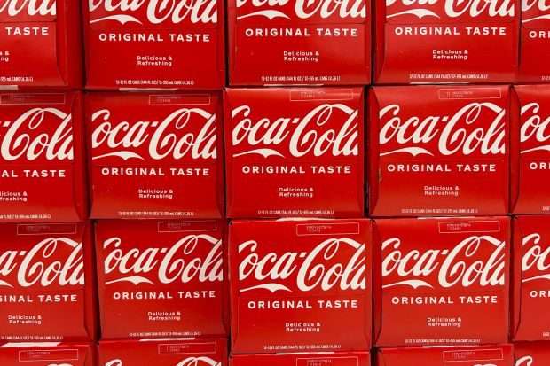 An image collage containing 1 images, Image 1 shows Close-up of several twelve-packs of Coca-Cola cans