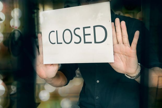 An image collage containing 1 images, Image 1 shows A person holding a "Closed" sign in a shop window