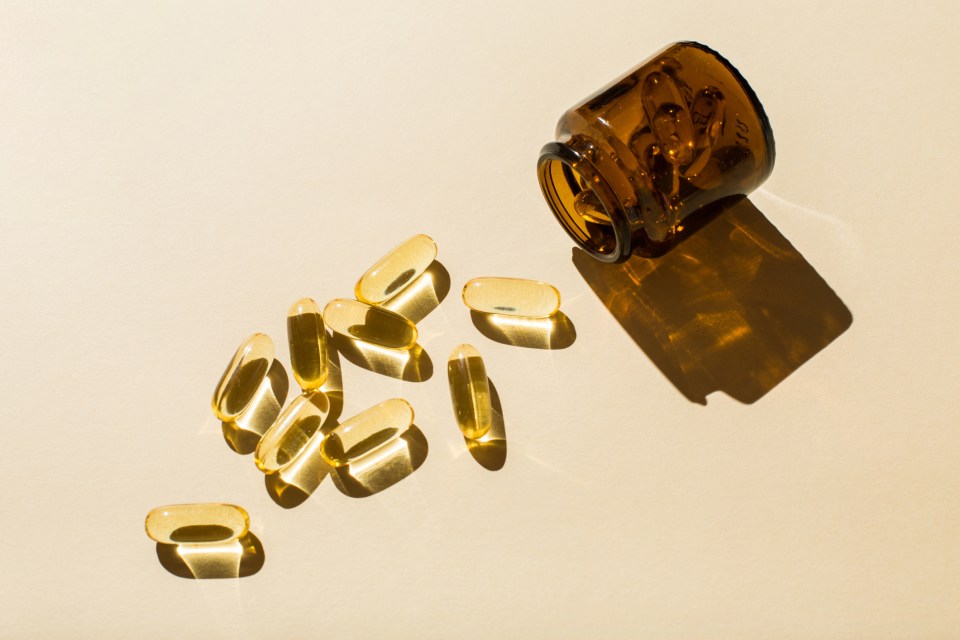 Omega-3 fish oil capsules spilled from a bottle.