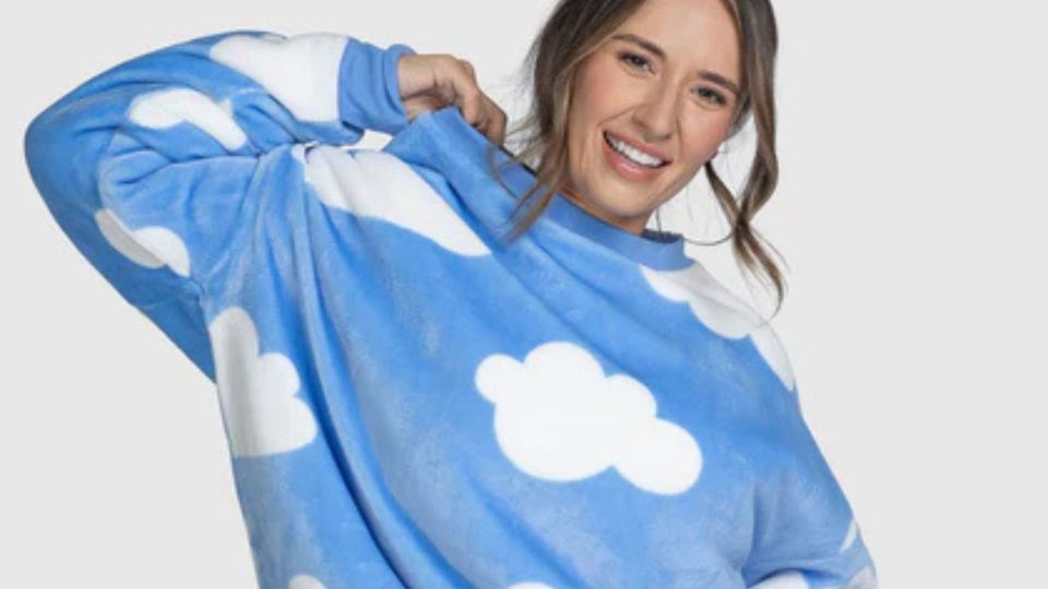 Woman smiling while wearing a blue cloud-patterned sweatshirt.