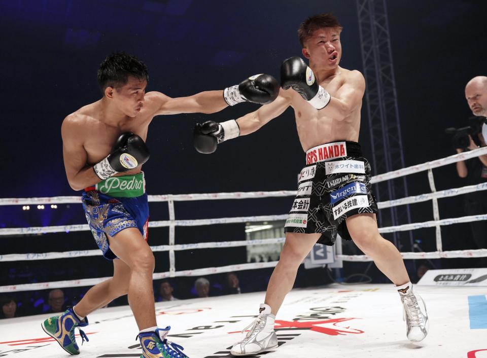 A boxer from the Philippines throws a punch at a Japanese boxer during an IBF minimumweight title match.