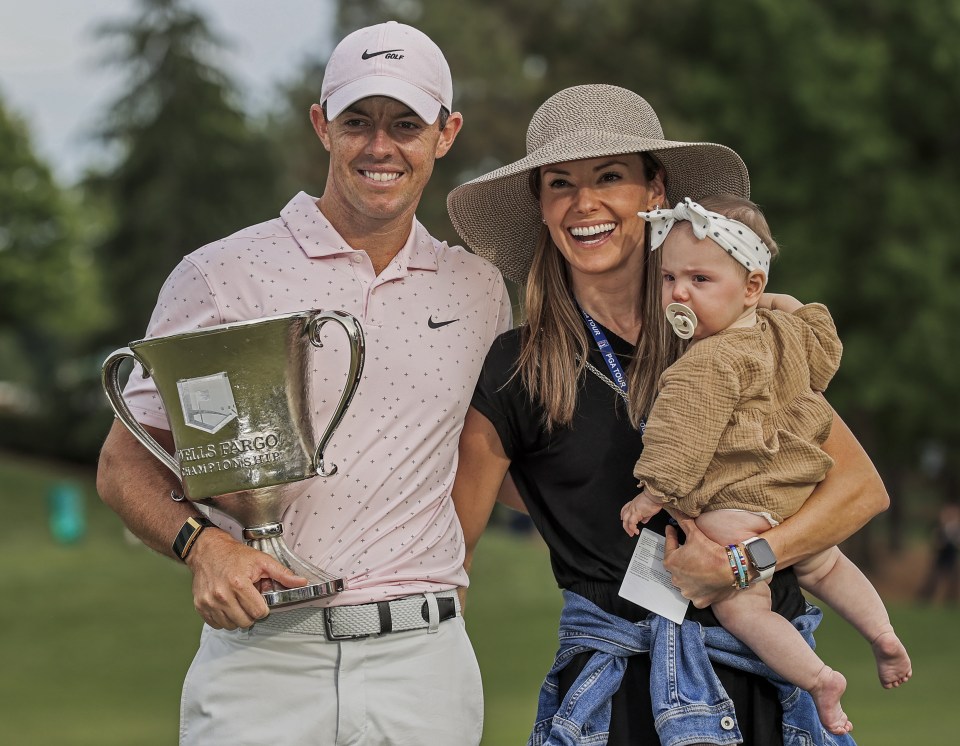 Rory McIlroy holding the Wells Fargo Championship trophy with his wife and daughter.