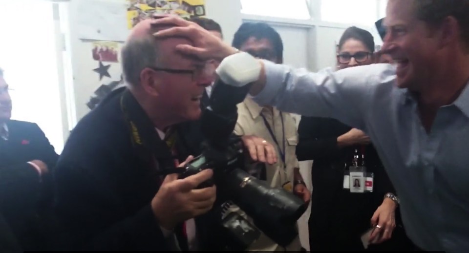 Prince Harry playfully placing a hand on a photographer's head.