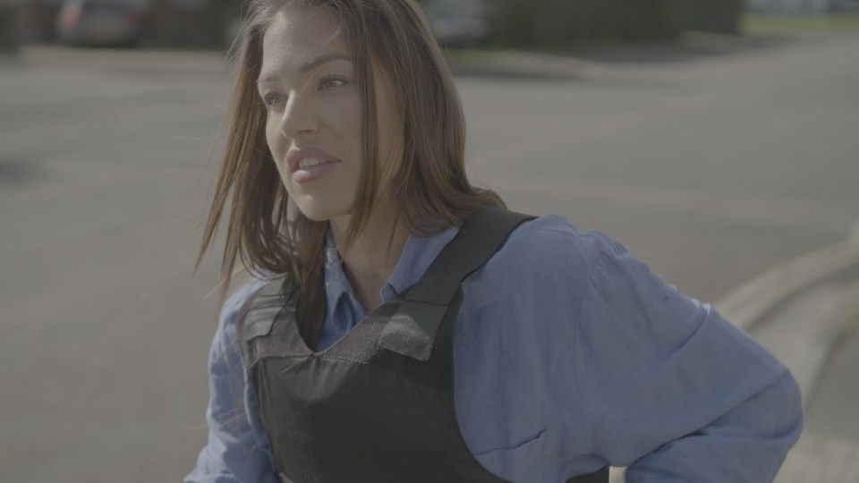 Woman in a bulletproof vest looking off to the side.