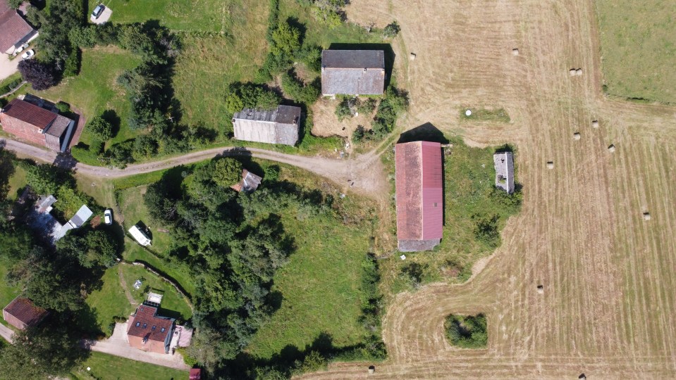Aerial view of a French village with farmhouses and surrounding fields.