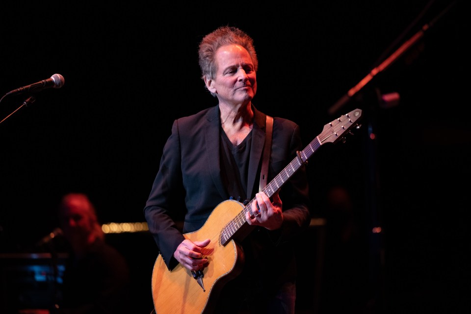 Lindsey Buckingham playing guitar onstage.