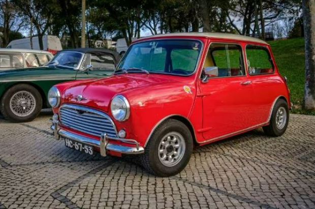 Red classic Mini Cooper parked on a cobblestone street.