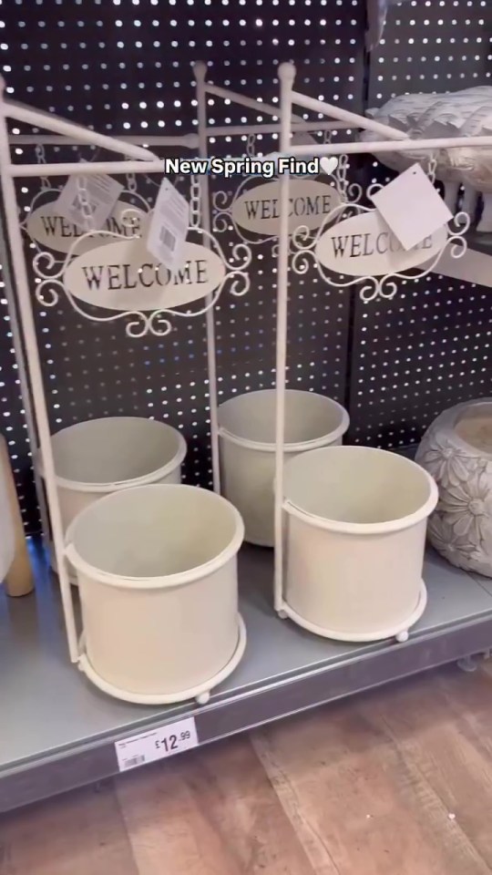 White metal planter stands with welcome signs and cream-colored pots.
