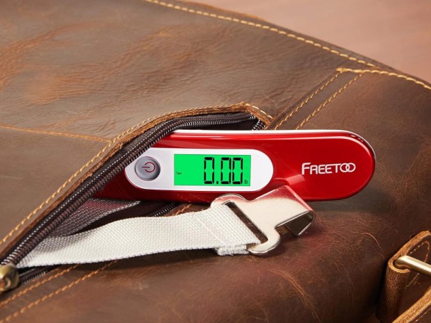Red Freetoo portable luggage scale in a brown leather bag.