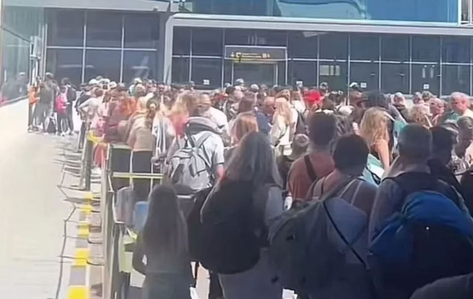 Large crowd of people waiting in a long line at an airport.