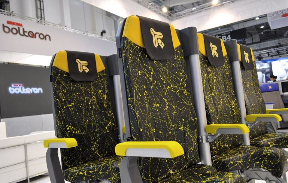 Stand-up airplane seats with yellow and black splatter design.