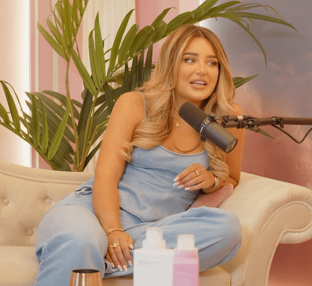 Woman sitting on a couch, speaking into a microphone.