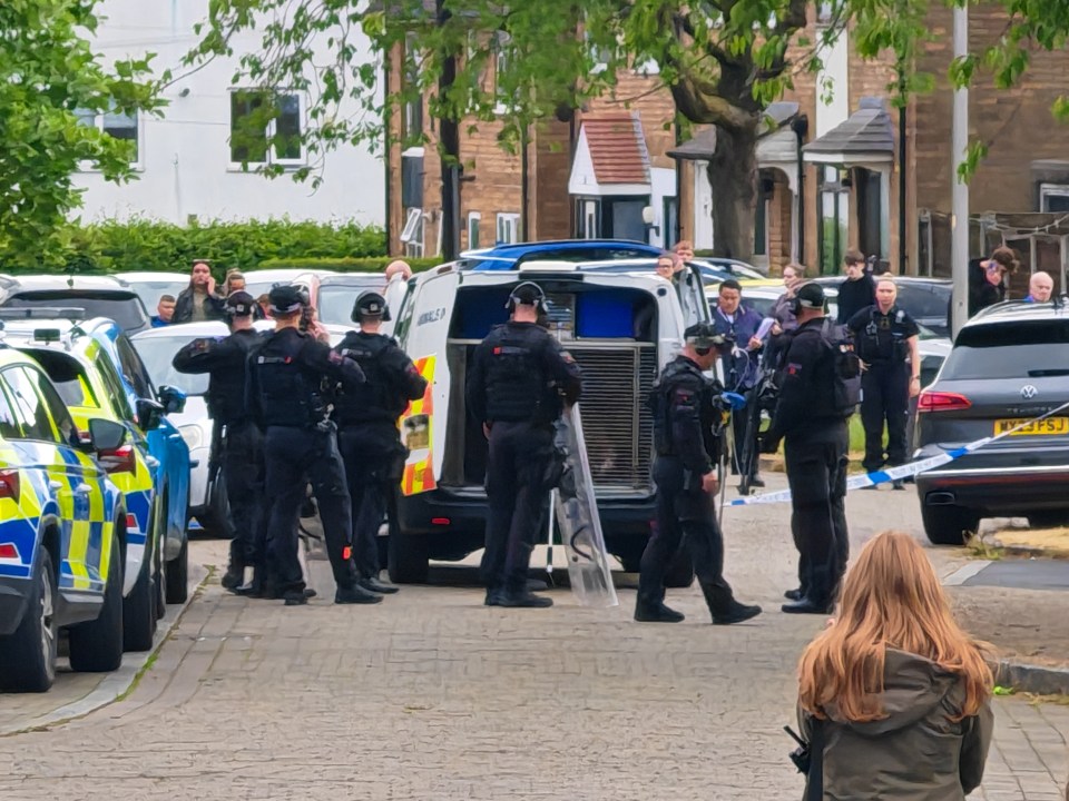 Police officers at a crime scene; a street is taped off.