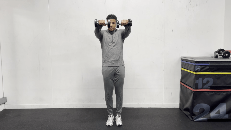 Man performing a shoulder workout with dumbbells.