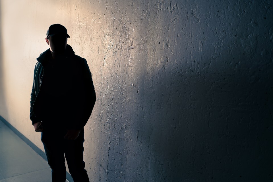 Silhouette of a suspicious man in a dark alley.