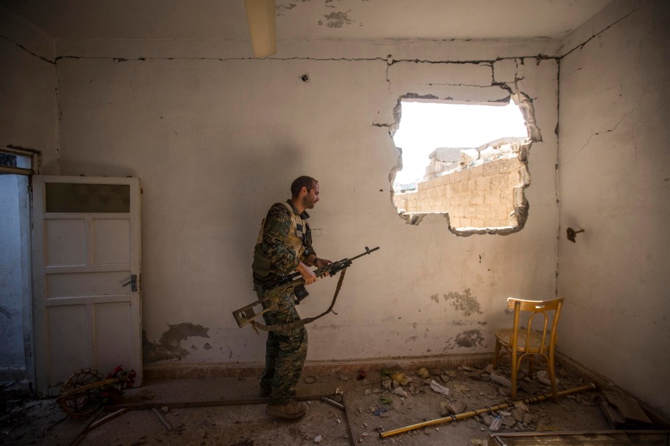 A British volunteer fighter with the Syriac Military Council holds a rifle in a damaged building in Raqqa, Syria.