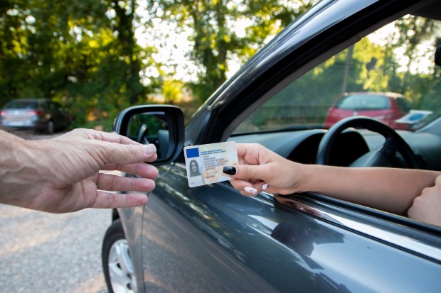 Teenager handing driver's license to police officer.