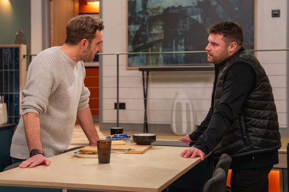 Aaron Dingle and John Sugden arguing in a kitchen.