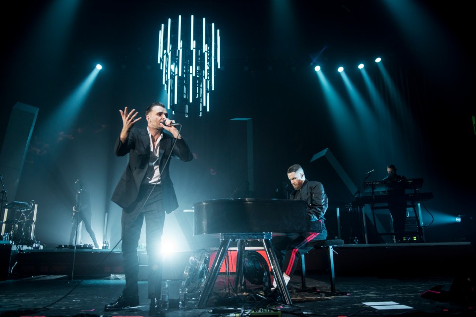Theo Hutchcraft and Adam Anderson of Hurts performing on stage.
