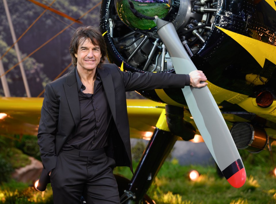 Tom Cruise at a premiere, leaning on a plane's propeller.