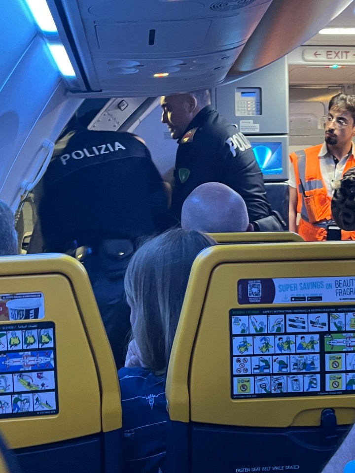 Police officers removing disruptive passengers from an airplane.