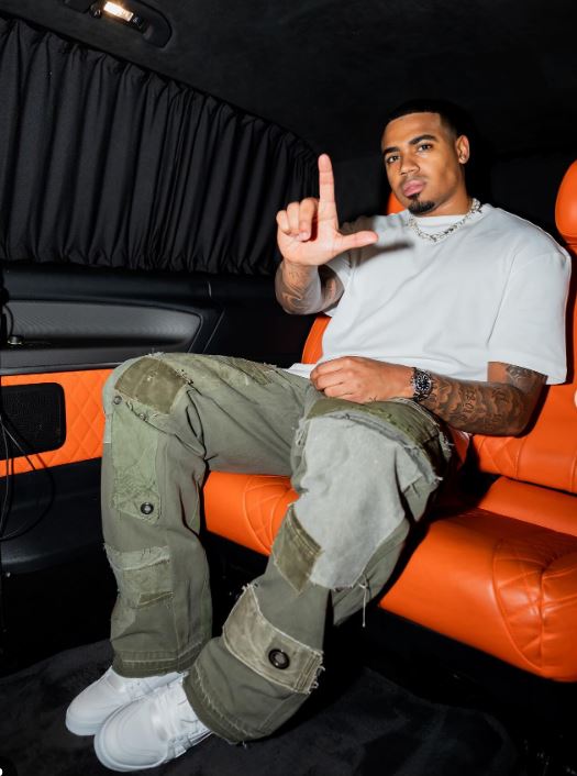 Man in a car making the "L" hand gesture.