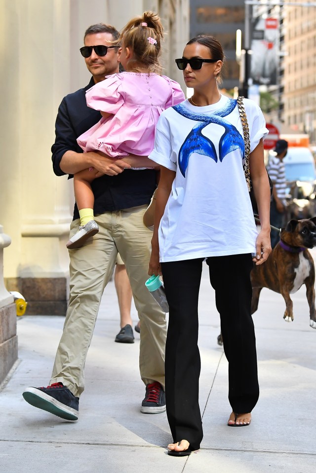 Irina Shayk, Bradley Cooper, and their daughter walking down a city street.
