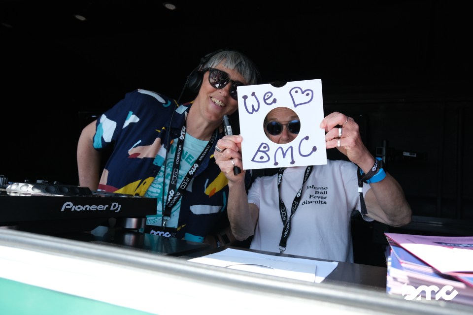 Two DJs at the Brighton Music Conference holding a sign that says "We ♥ BMC".