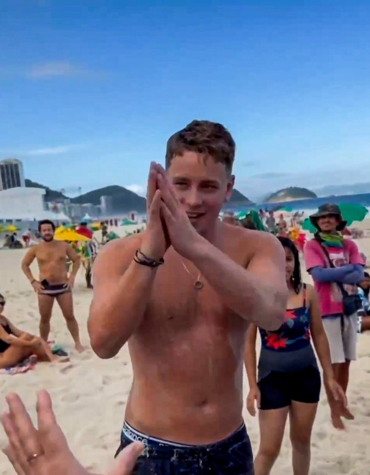 British tourist Jensen Sturgeond thanking rescuers on Copacabana Beach in Brazil after being rescued from the sand.
