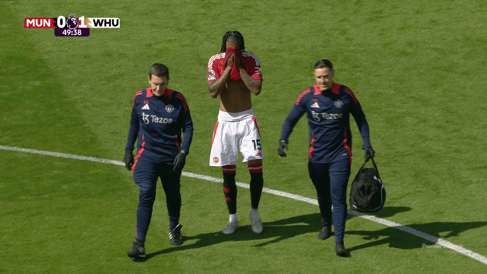 Soccer player being escorted off the field by medical staff.