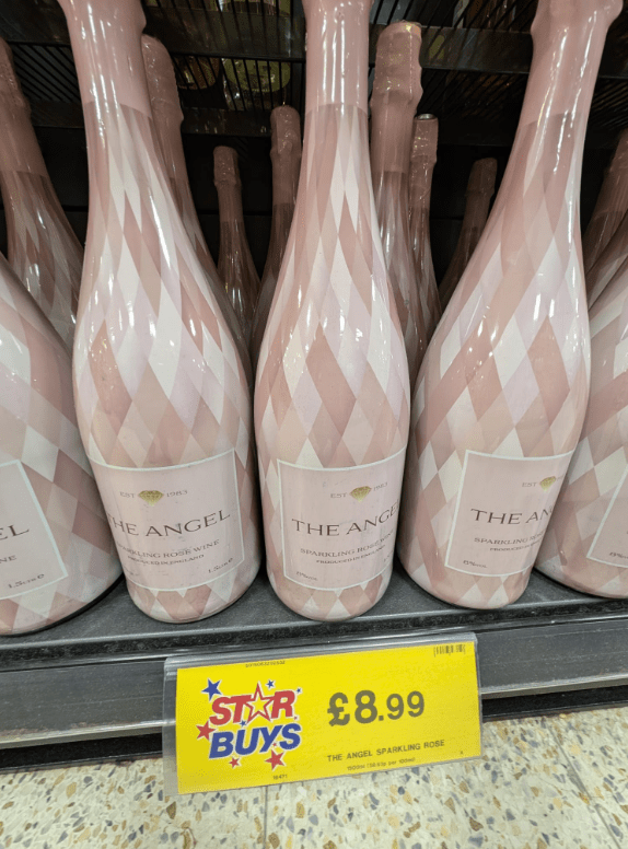 Several bottles of The Angel Sparkling Rosé wine on a store shelf.