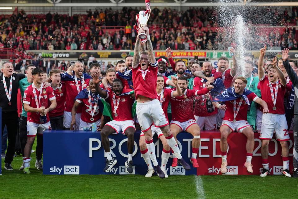 Wrexham soccer team celebrating a victory, raising a trophy.
