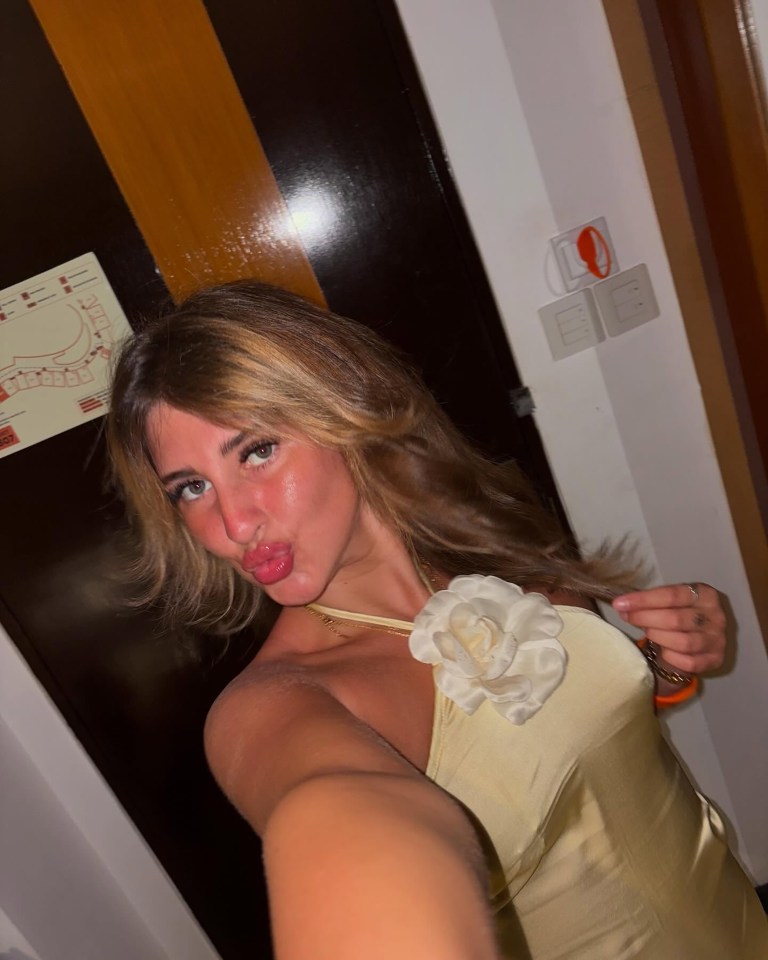 Selfie of a woman pursing her lips, wearing a pale yellow halter top.