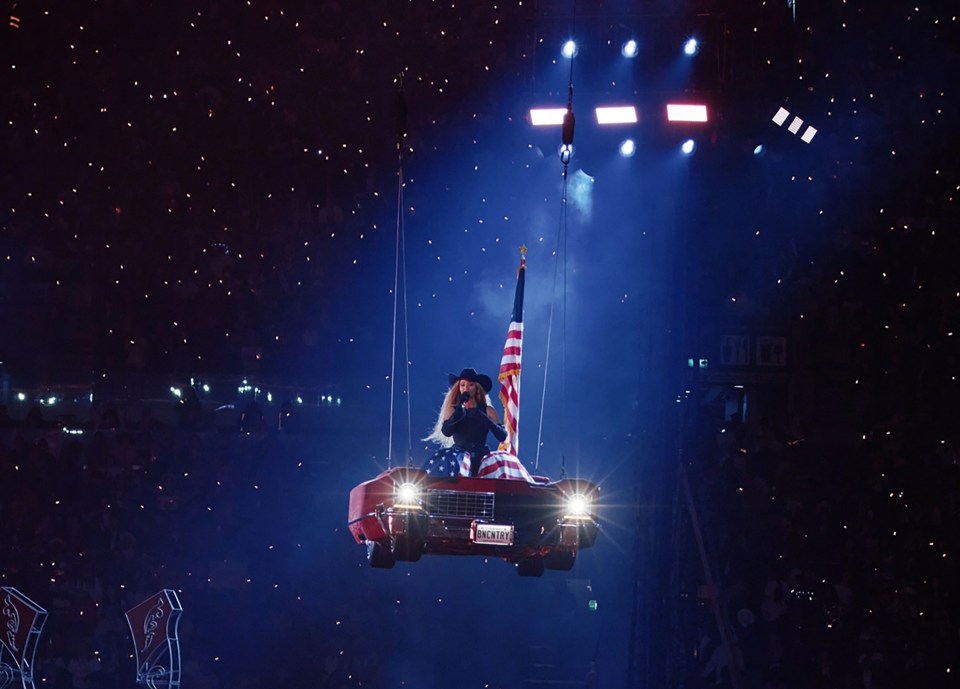 Beyoncé performing on a car suspended above a concert audience.