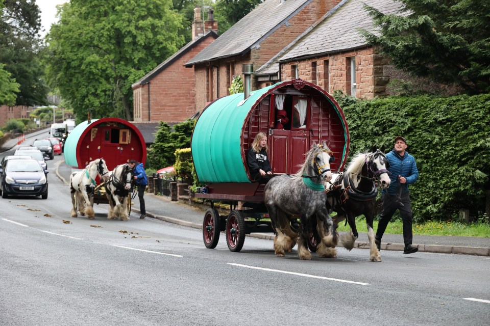 Horses pulling wagons down a road.