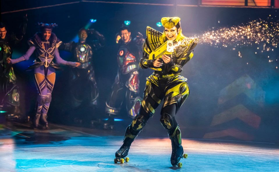 Roller skater in a futuristic costume firing a sparkling weapon.