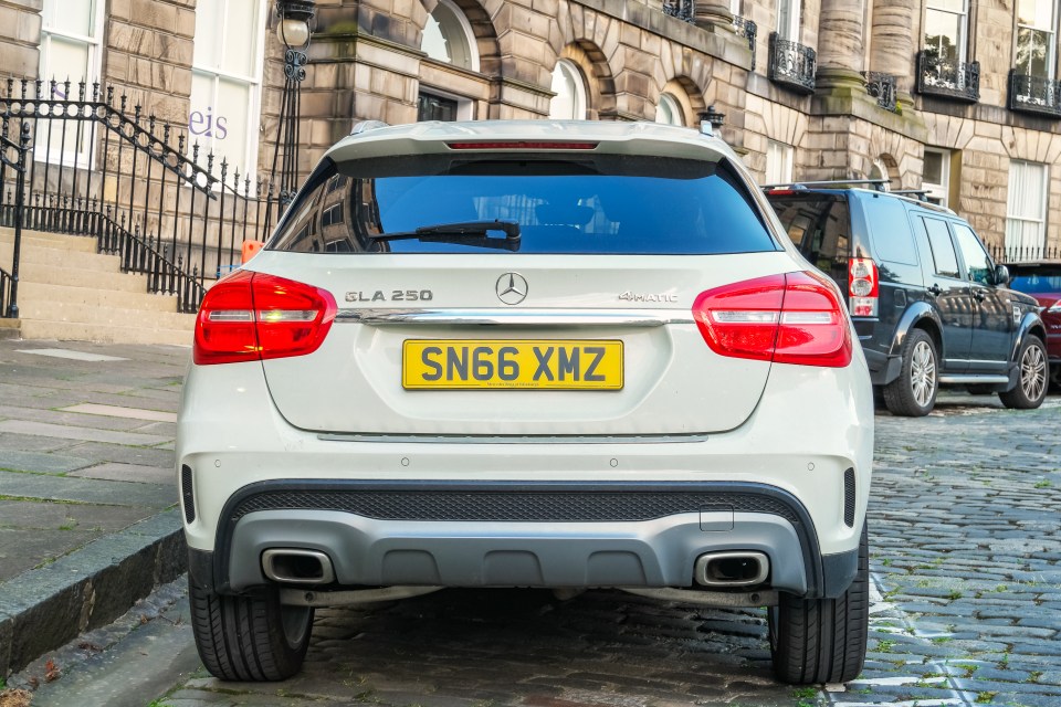Rear view of a white Mercedes GLA 250 parked on a cobblestone street.