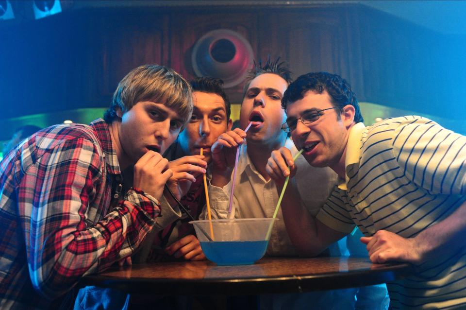 Four young men sharing a punch bowl with straws.