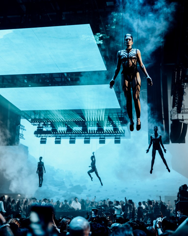 Performers suspended above a concert crowd.