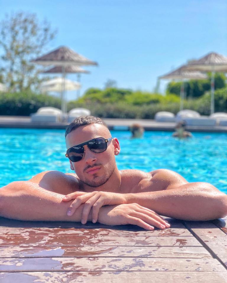 Man in sunglasses relaxing by a pool.
