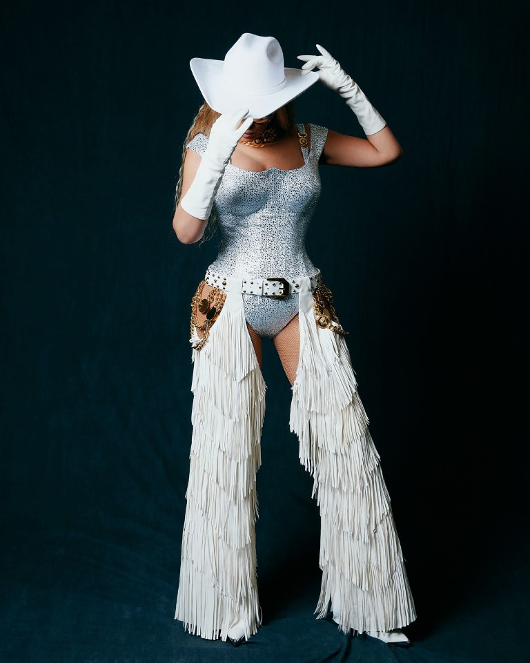 Beyoncé in a white cowboy hat and fringed chaps at a concert.