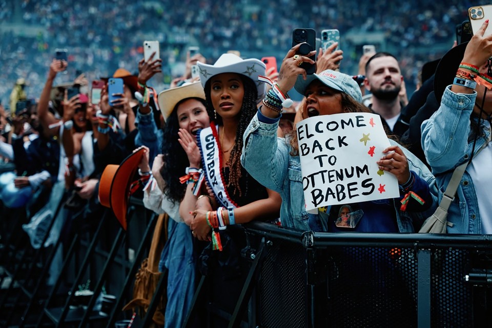 Concertgoers holding up phones and a sign that says "Welcome back to Ottenum Babes".