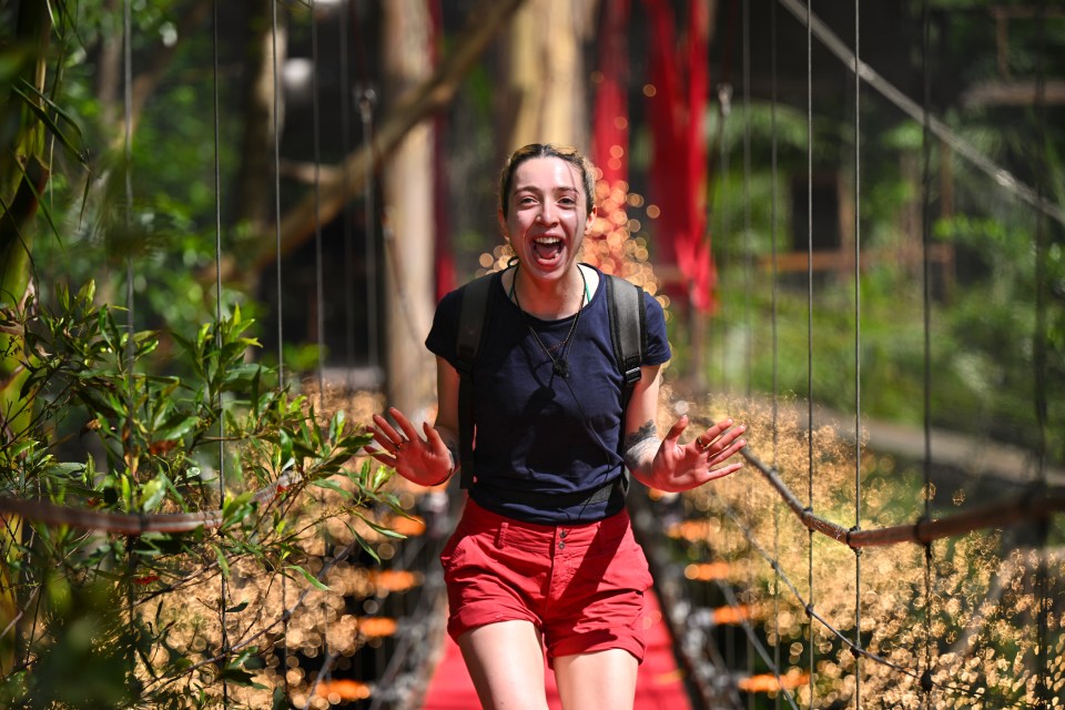 A smiling woman walks across a bridge, celebrating her eviction from a reality TV show.