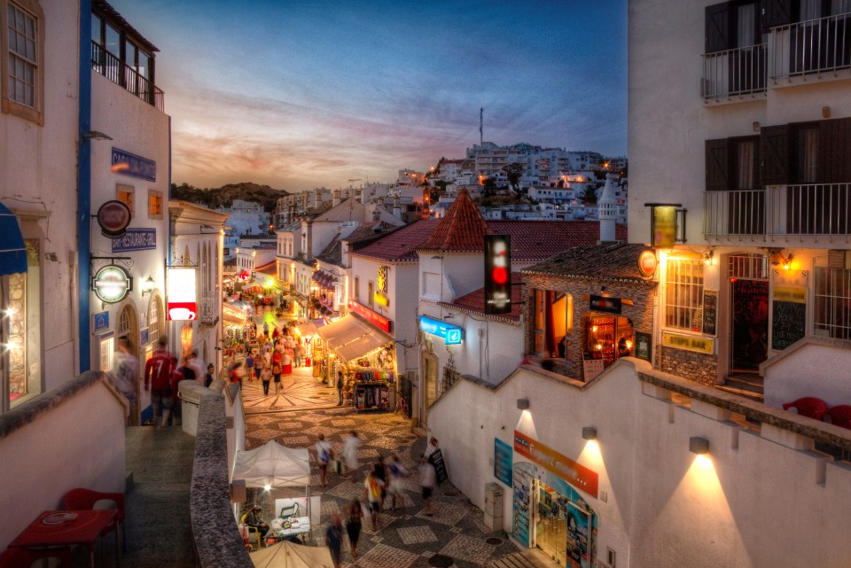 Albufeira's historical center at sunset, with tourists and shops.