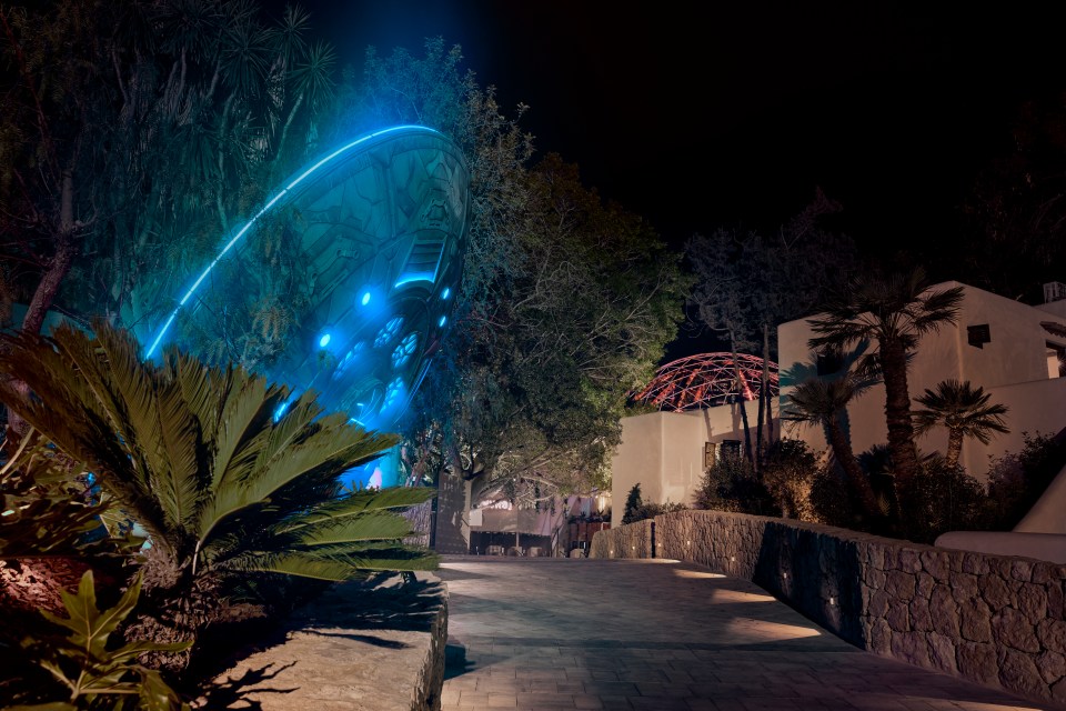 Night view of UNVRS nightclub in Ibiza, featuring a large, illuminated structure resembling a spaceship.
