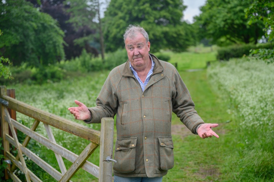 Jeremy Clarkson standing by a gate with his arms outstretched.