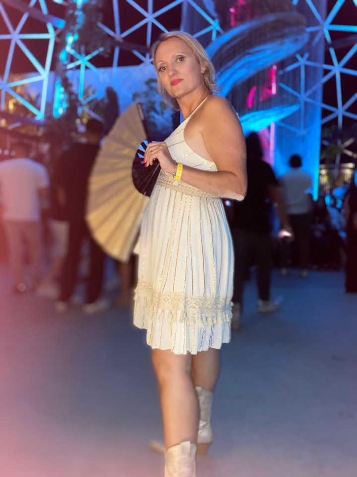 Woman in white dress holding a hand fan.