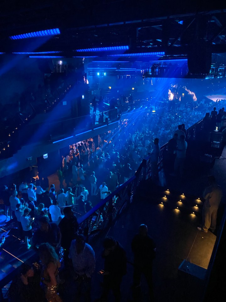 Crowded nightclub with blue lighting.