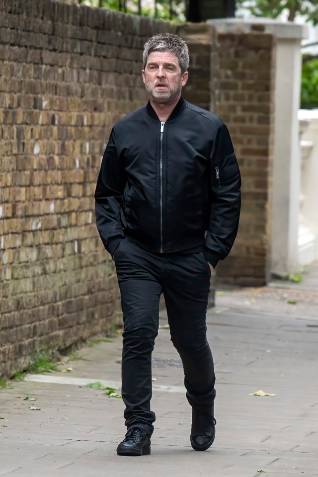 Noel Gallagher walking down a street.