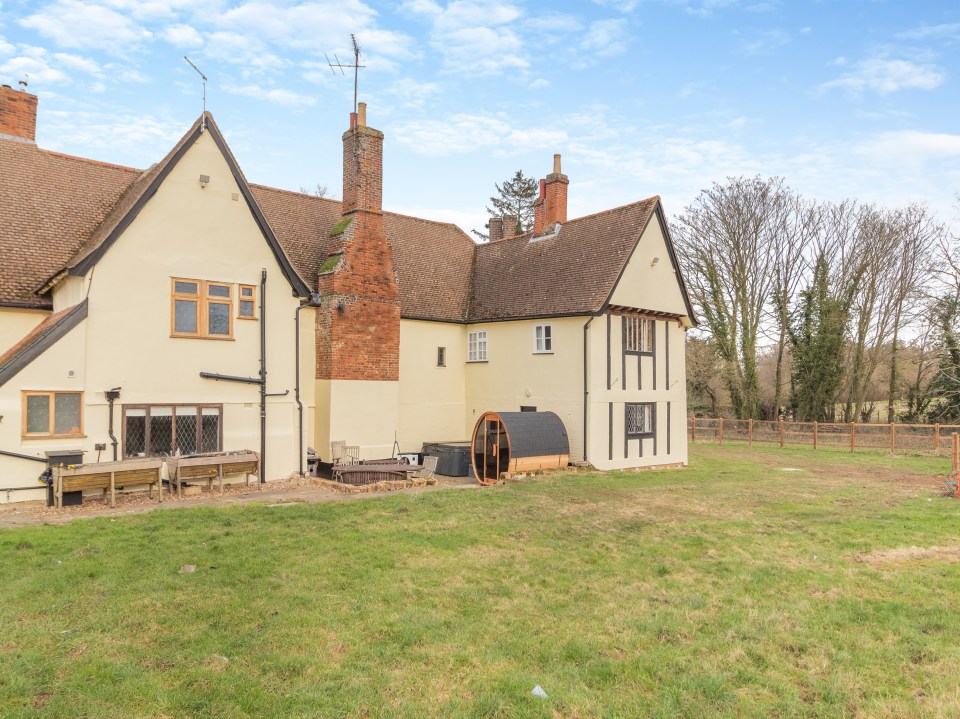 Farmhouse with hot tub and surrounding yard.